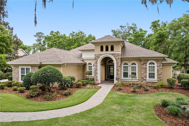 mediterranean / spanish-style house featuring stucco siding, stone siding, and a front yard