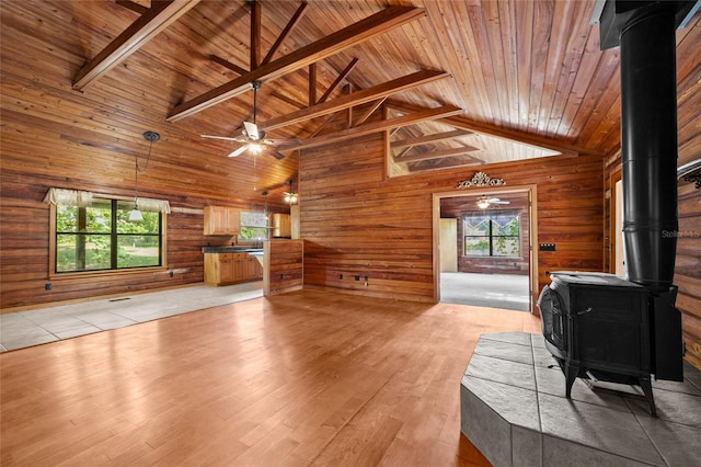 unfurnished living room featuring plenty of natural light, a wood stove, and wood ceiling