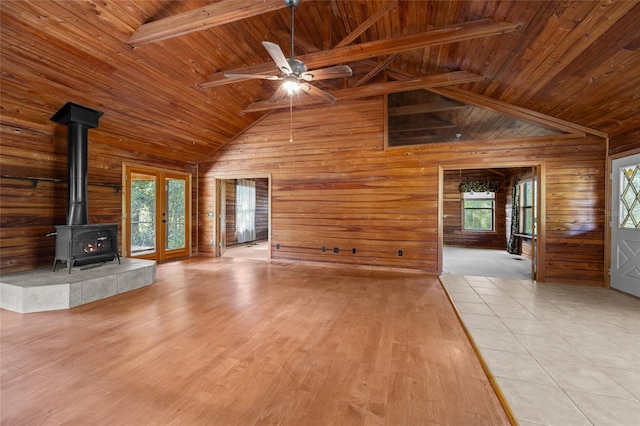 unfurnished living room featuring wood walls, wood ceiling, and a wood stove