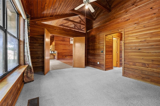 carpeted spare room featuring ceiling fan, wood walls, and wooden ceiling