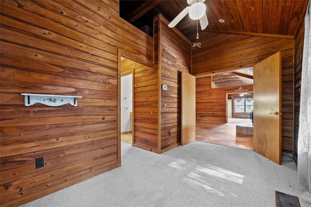 spare room with wood ceiling, a ceiling fan, wood walls, lofted ceiling, and carpet flooring