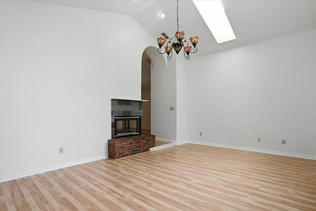 7800 SW 24th Ave, Gainesville, FL 32607 - unfurnished living room with a skylight, wood finished floors, high vaulted ceiling, arched walkways, and a fireplace