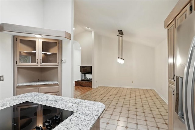 7800 SW 24th Ave, Gainesville, FL 32607 - kitchen with stainless steel fridge with ice dispenser, black electric cooktop, vaulted ceiling, glass insert cabinets, and pendant lighting