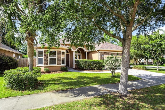 view of front of property featuring fence, stucco siding, a front lawn, and stone siding