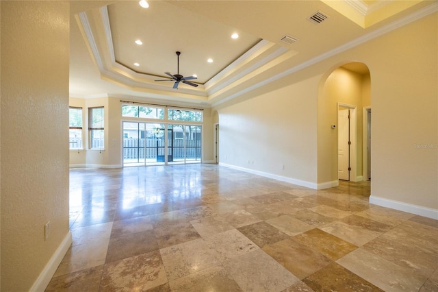 unfurnished room featuring crown molding, visible vents, ceiling fan, a tray ceiling, and arched walkways
