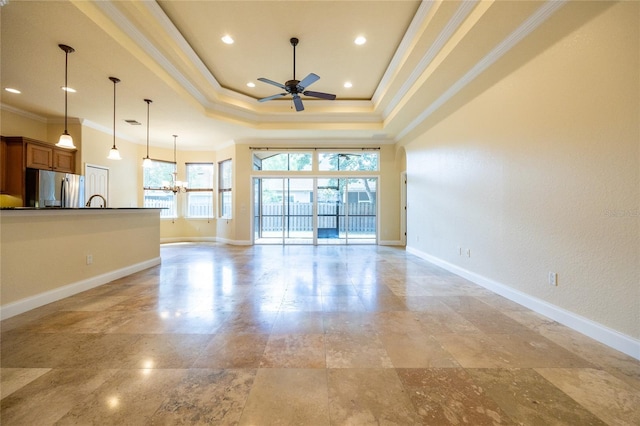 unfurnished living room featuring crown molding, ceiling fan with notable chandelier, recessed lighting, baseboards, and a tray ceiling