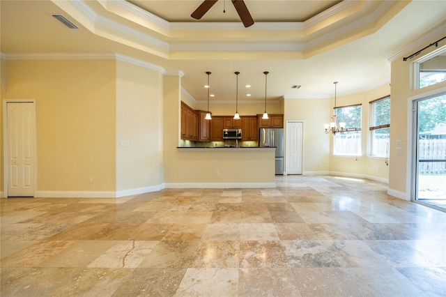 unfurnished living room with visible vents, crown molding, baseboards, a tray ceiling, and ceiling fan with notable chandelier