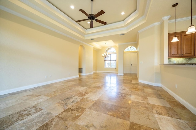 empty room featuring arched walkways, ceiling fan with notable chandelier, baseboards, a tray ceiling, and ornamental molding