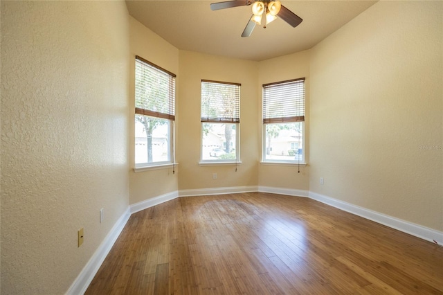 spare room with baseboards, a ceiling fan, a textured wall, and wood finished floors