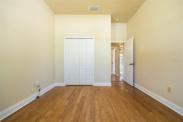 unfurnished bedroom with visible vents, light wood finished floors, baseboards, and a closet