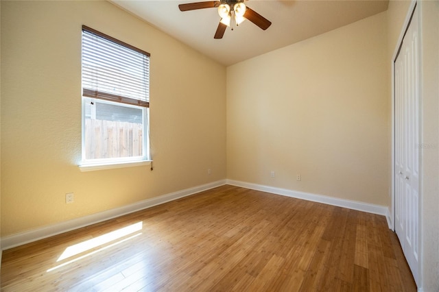 unfurnished bedroom featuring a closet, baseboards, ceiling fan, and wood finished floors