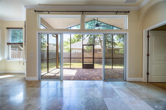 entryway featuring crown molding, baseboards, a ceiling fan, and stone tile floors