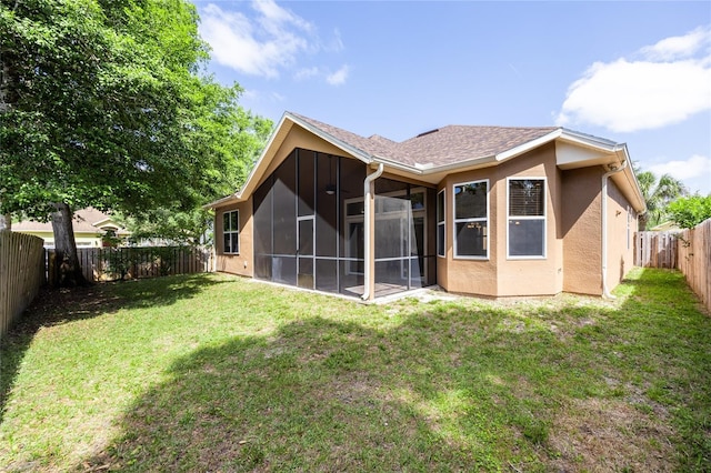 back of house with a fenced backyard, a sunroom, stucco siding, and a yard