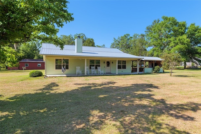 back of house with a porch, a yard, a chimney, and metal roof