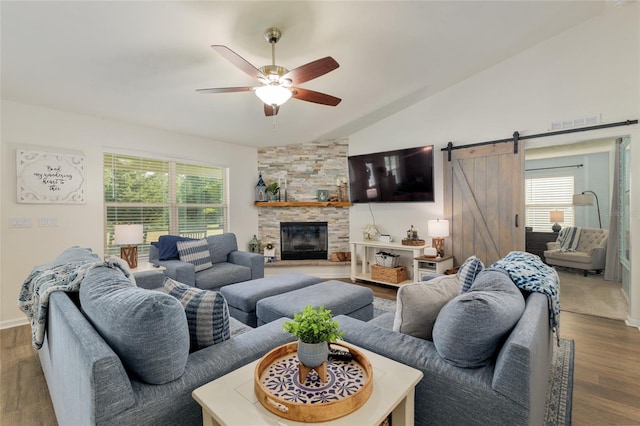 living area featuring a ceiling fan, a barn door, wood finished floors, and lofted ceiling