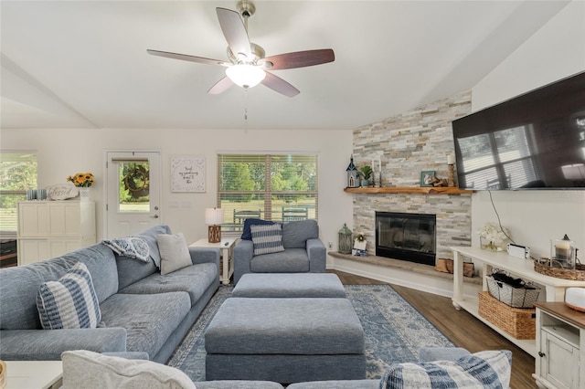 living area featuring a stone fireplace, a ceiling fan, dark wood-style floors, and vaulted ceiling