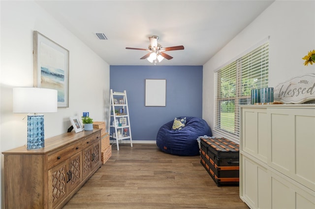 sitting room featuring visible vents, a ceiling fan, light wood finished floors, and baseboards