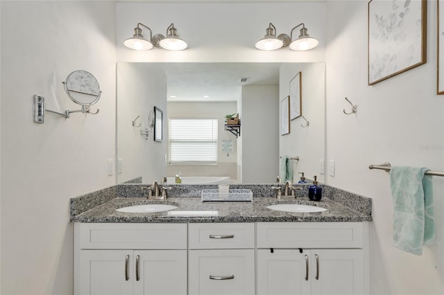 bathroom with double vanity, a sink, and a bath
