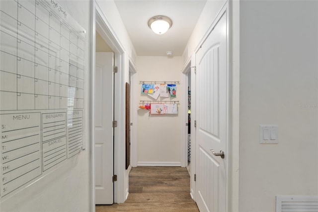 corridor featuring baseboards and wood finished floors