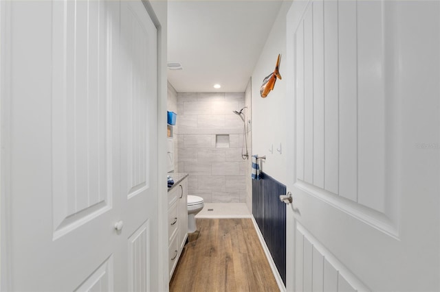 bathroom featuring vanity, toilet, recessed lighting, wood finished floors, and tiled shower