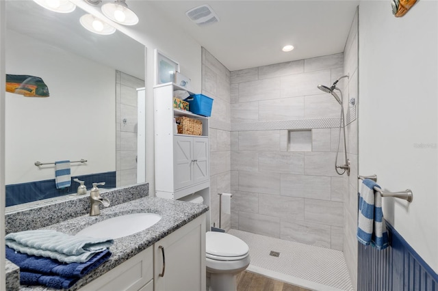 full bath with a tile shower, vanity, toilet, recessed lighting, and visible vents