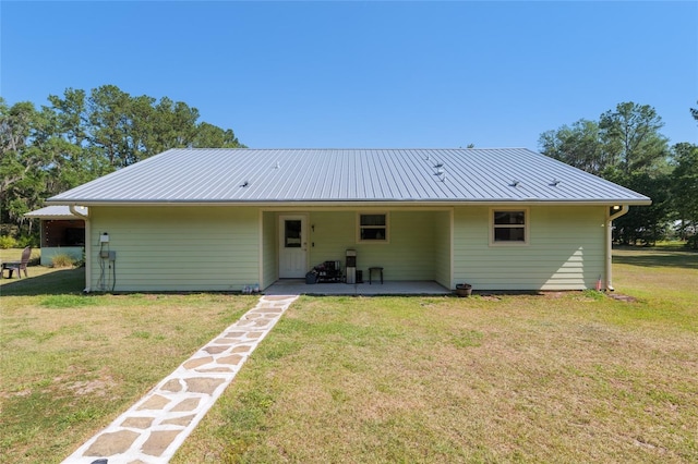 back of house with a lawn and metal roof