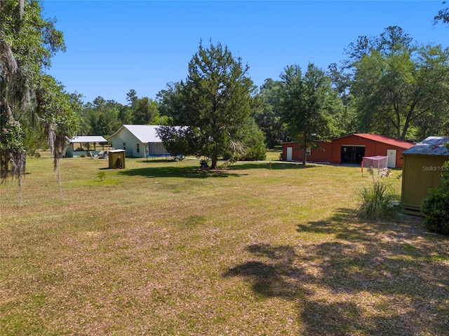 view of yard featuring a garage, an outbuilding, and a pole building