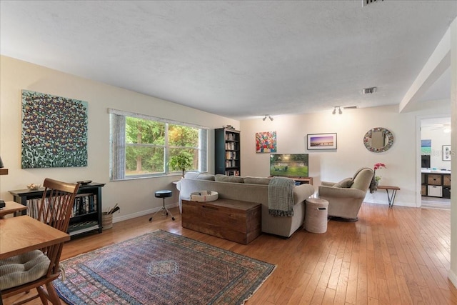 living room with baseboards, visible vents, and light wood-style flooring