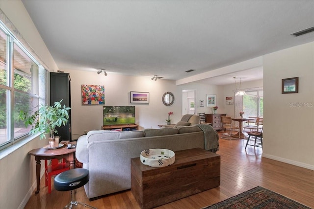 living area with baseboards, light wood finished floors, and visible vents