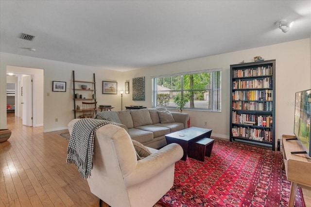 living area featuring visible vents, baseboards, and wood finished floors