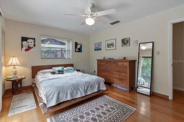 bedroom featuring baseboards, visible vents, multiple windows, and hardwood / wood-style floors