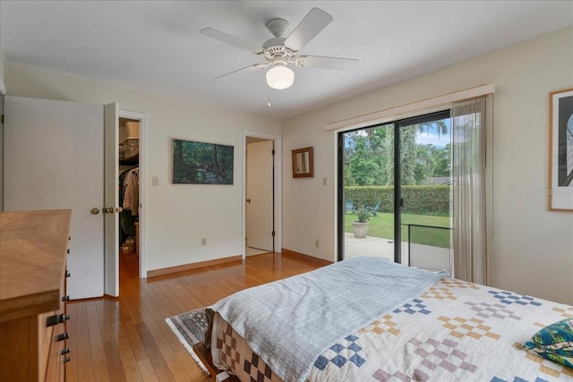 bedroom featuring a walk in closet, a ceiling fan, baseboards, wood-type flooring, and access to outside