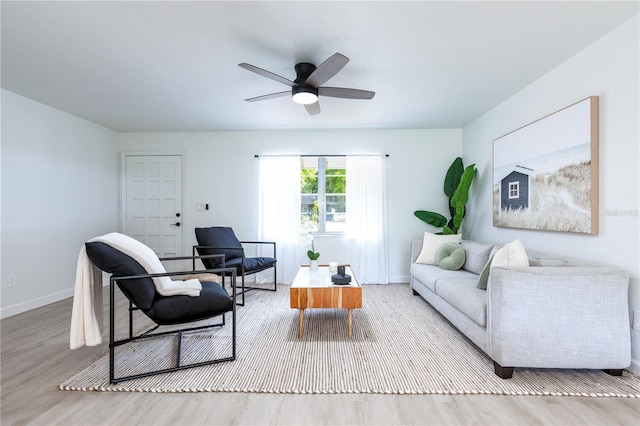 living area with baseboards, a ceiling fan, and wood finished floors