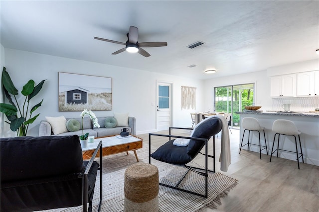 living area with a ceiling fan, baseboards, visible vents, and light wood-style flooring
