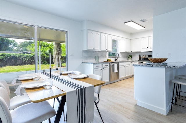 kitchen featuring light stone countertops, appliances with stainless steel finishes, a breakfast bar area, decorative backsplash, and visible vents