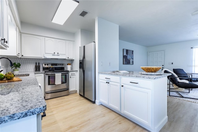 kitchen with appliances with stainless steel finishes, a sink, light wood finished floors, a peninsula, and under cabinet range hood