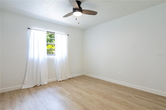 empty room featuring a ceiling fan, baseboards, and light wood finished floors