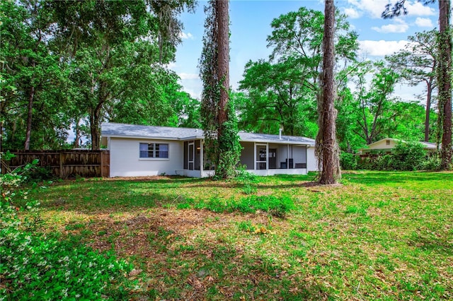 rear view of house with a yard, fence, and a sunroom
