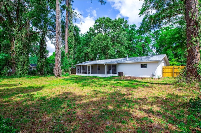 back of house featuring a sunroom, central AC unit, a lawn, and fence