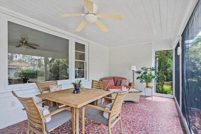 sunroom / solarium featuring a ceiling fan, wood ceiling, stone finish flooring, and outdoor dining space