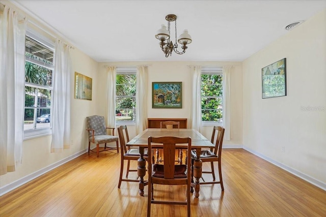 dining space with visible vents, an inviting chandelier, a wealth of natural light, and light wood-style flooring