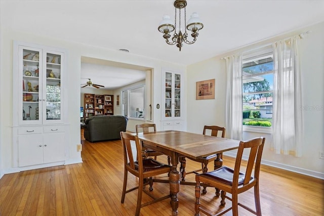 dining room featuring light wood-style floors, baseboards, and ceiling fan with notable chandelier