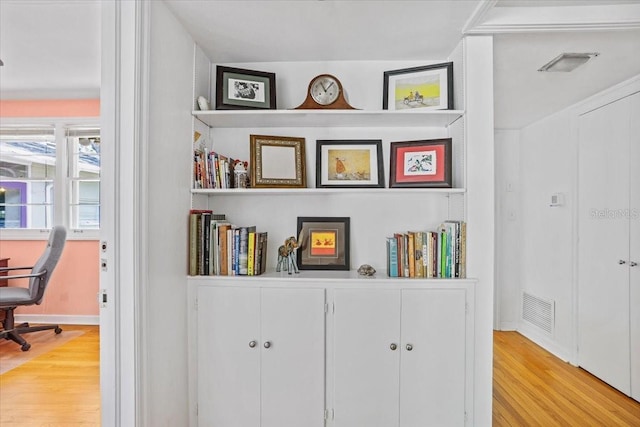 hall with light wood-style floors, baseboards, and visible vents