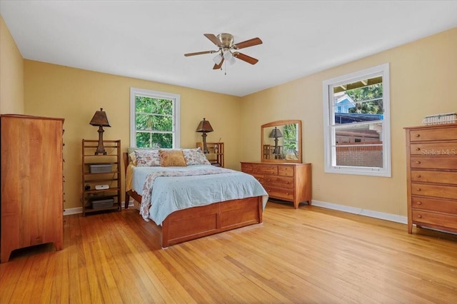 bedroom with baseboards, multiple windows, and light wood-style floors