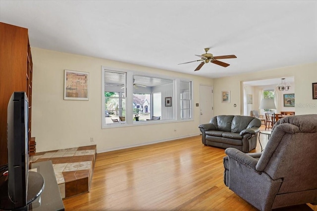 living area with a ceiling fan, baseboards, and light wood-style flooring