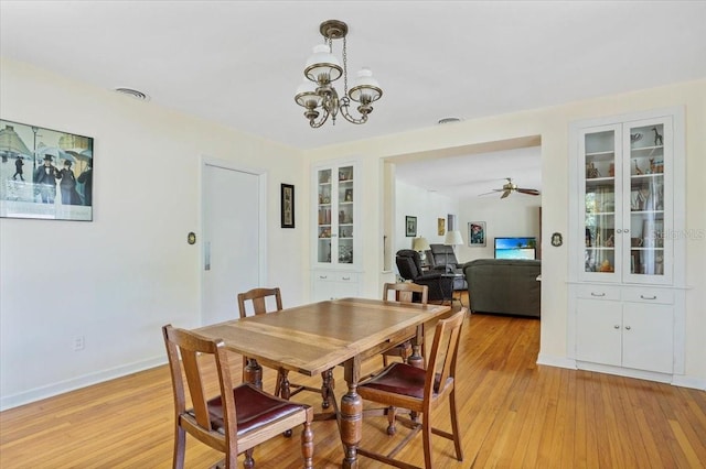 dining room featuring visible vents, built in features, baseboards, light wood-style flooring, and ceiling fan with notable chandelier
