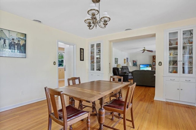 dining area featuring baseboards, ceiling fan with notable chandelier, light wood-style flooring, and visible vents