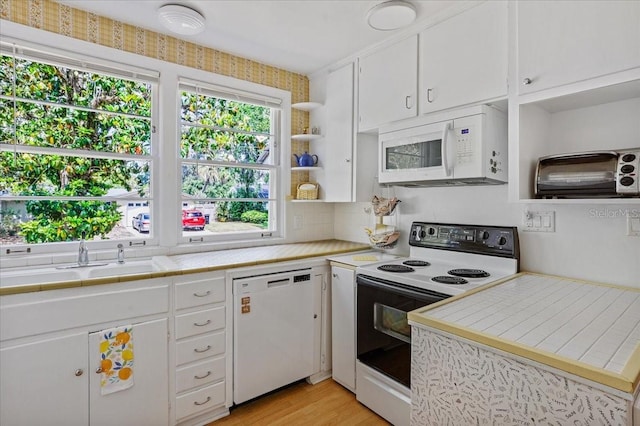 kitchen with light wood-style floors, tile counters, white appliances, and white cabinets