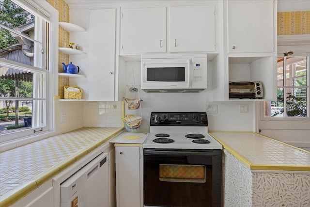 kitchen featuring open shelves, white appliances, tile countertops, white cabinetry, and backsplash