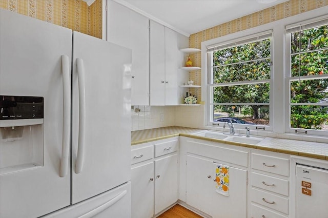 kitchen featuring a sink, tile counters, white appliances, and a wealth of natural light